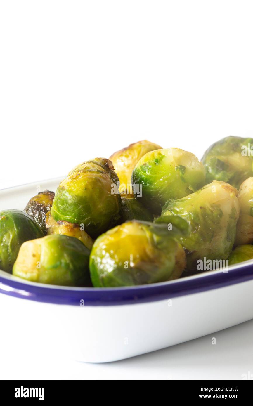 Brussels sprouts, oven roasted in olive oil,  in an enamel dish bowl. Isolated on a white background Stock Photo