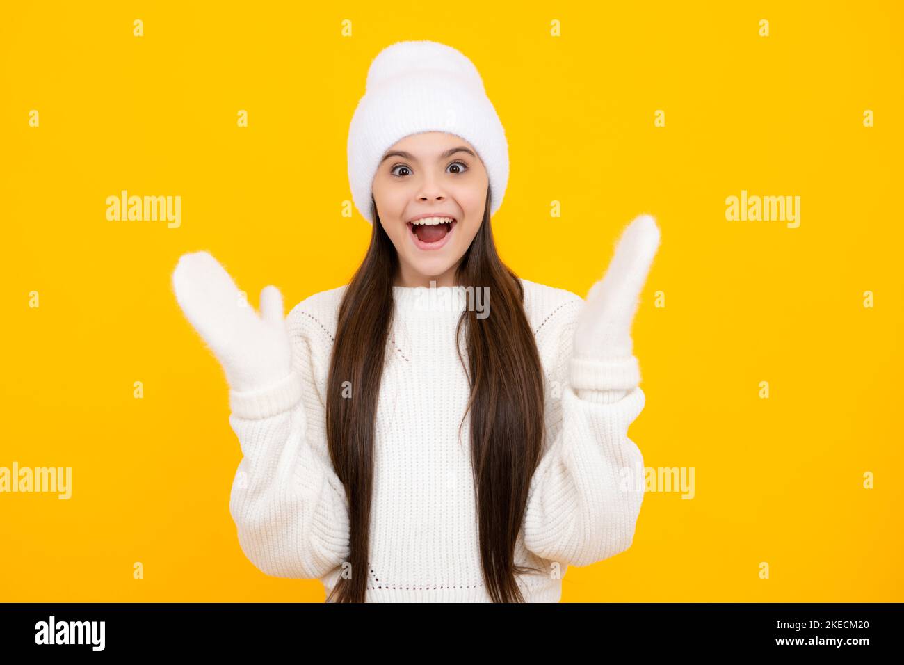 Child with positive expression, joyful and exciting, dressed in casual winter cloth over yellow background with empty space. Happy teenager girl Stock Photo