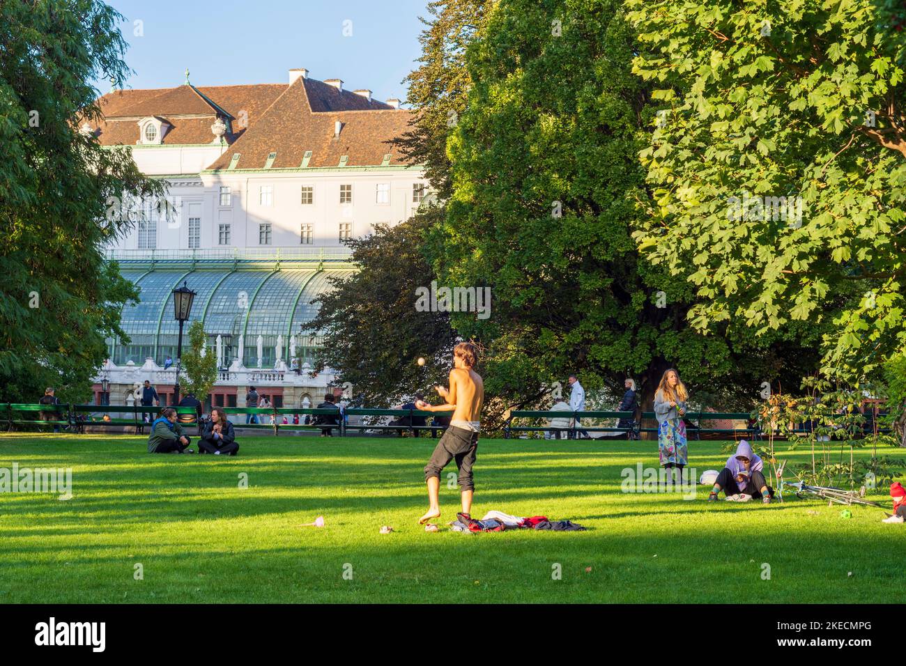 Vienna, park Burggarten, house Palmenhaus, juggler, people on meadow in 01. Old Town, Wien, Austria Stock Photo