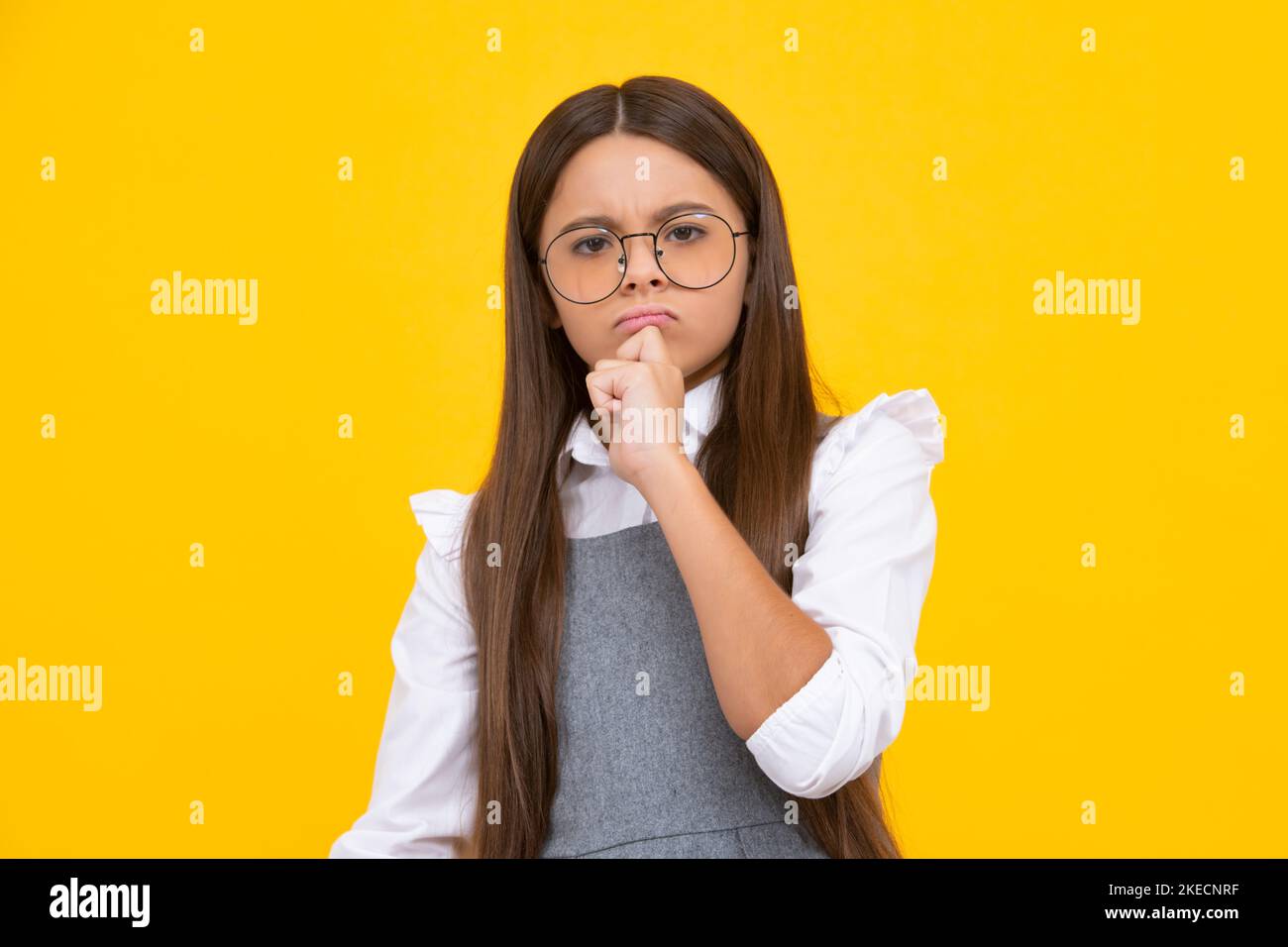 Beautiful teenager child over isolated yellow background with hand on chin thinking about question, thoughtful face. Doubt concept. Thinking face Stock Photo