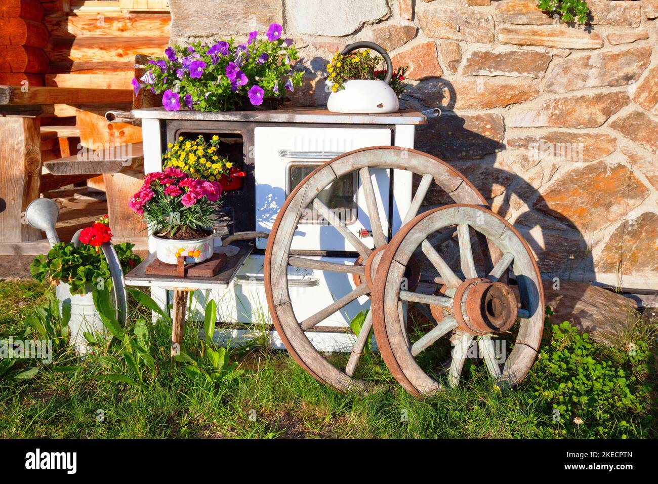 Decoration with flowers, spoke wheels and stove on the Spitzner Alm in the Ulten Valley, South Tyrol Stock Photo