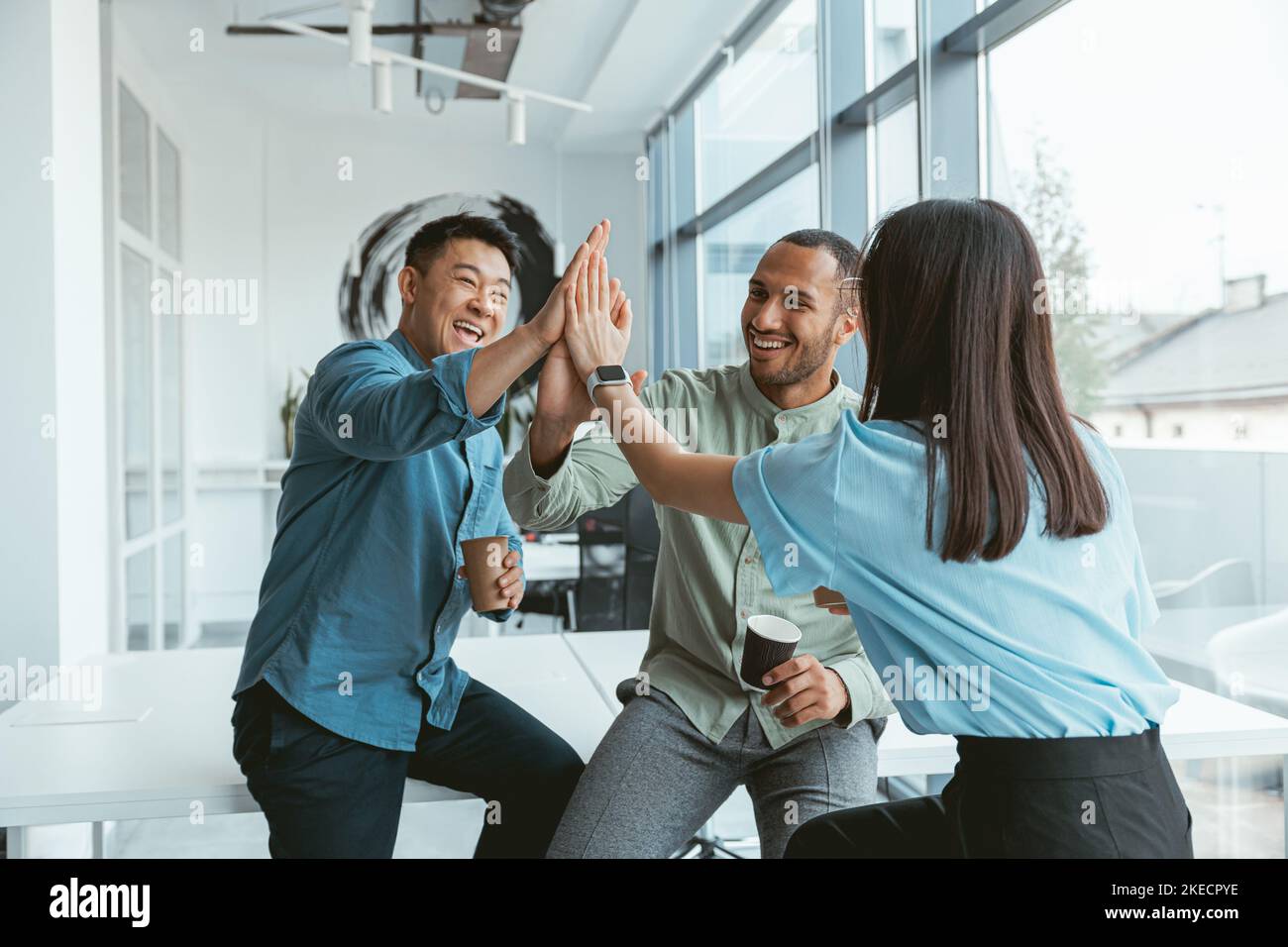 Smiling group of multiethnic colleagues drinking coffee and talking during break Stock Photo