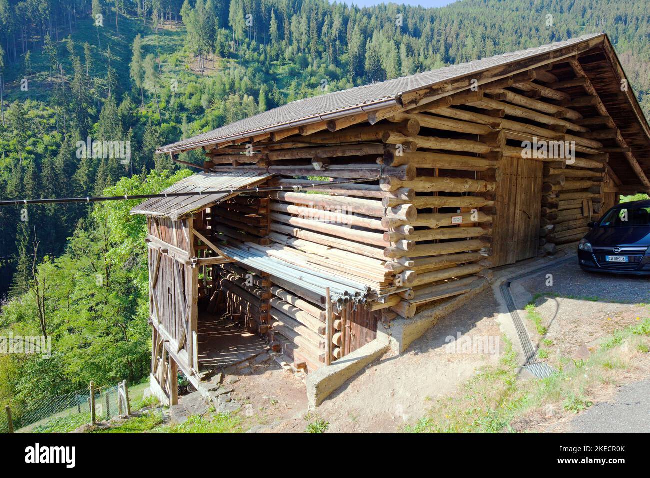 Barn on steep slope built of round beams with air passage, mountain farm in South Tyrolean Ulten Valley Stock Photo