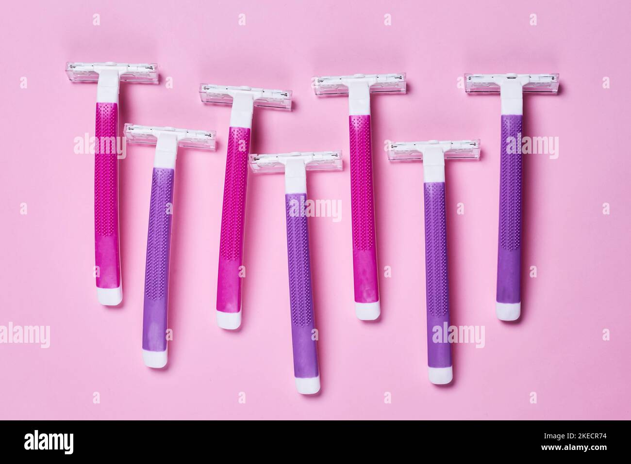 three purple and white razors on a pink background with copy space in ...