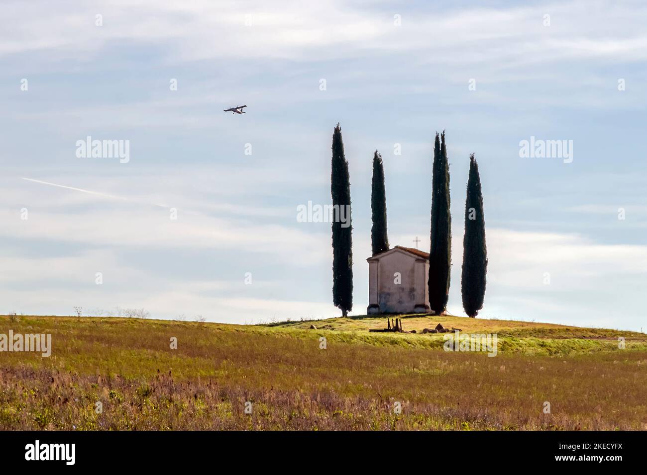 A small touring plane flies over the ancient Church of San Pierino in Camugliano, Ponsacco, Pisa, Italy Stock Photo