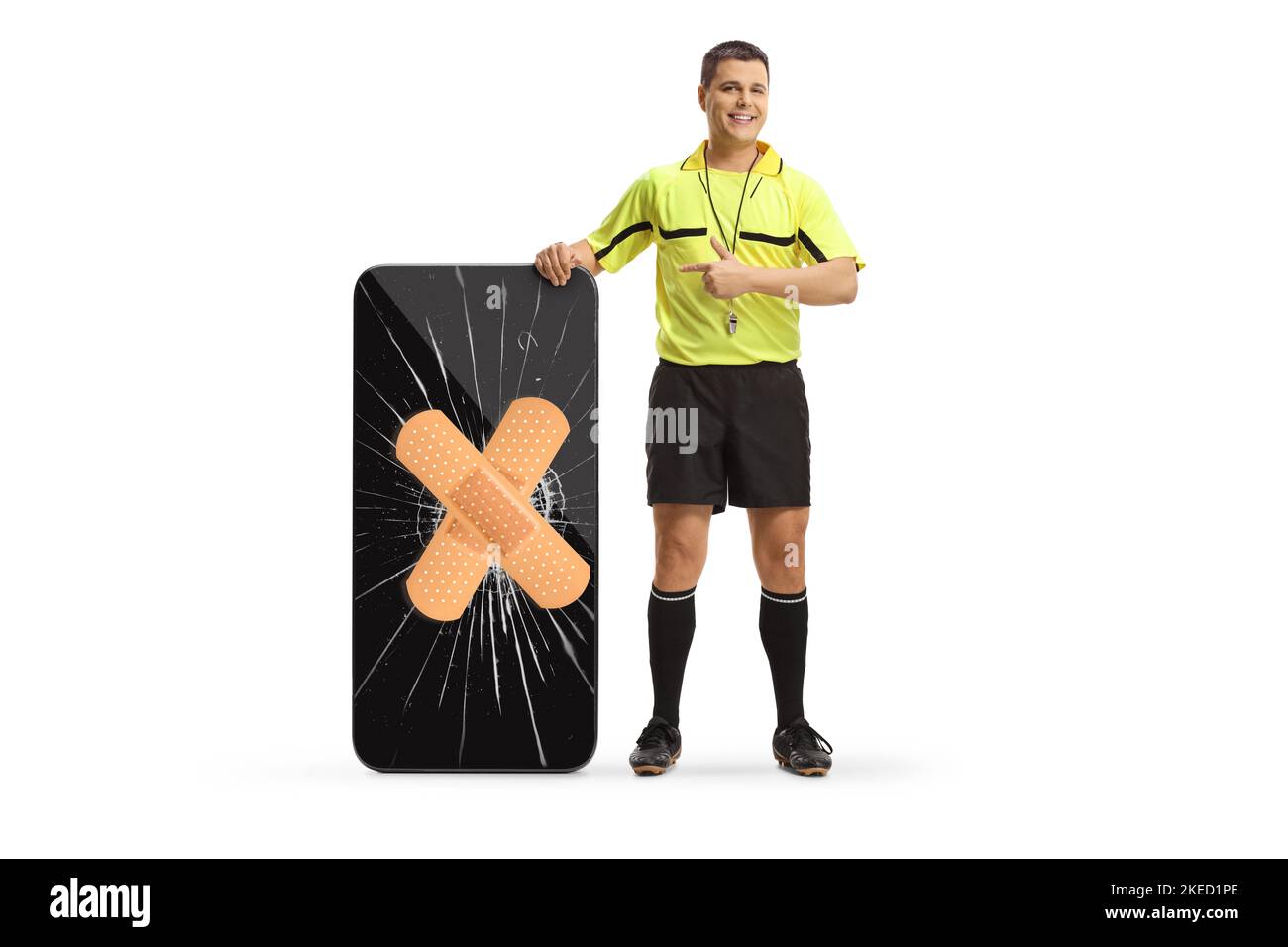 Full length portrait of a football referee pointing at a smartphone with broken screen fixed with bandage isolated on white background Stock Photo