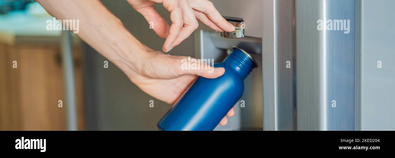 Male hand is pouring cold water and ice cubes in a metal bottle from