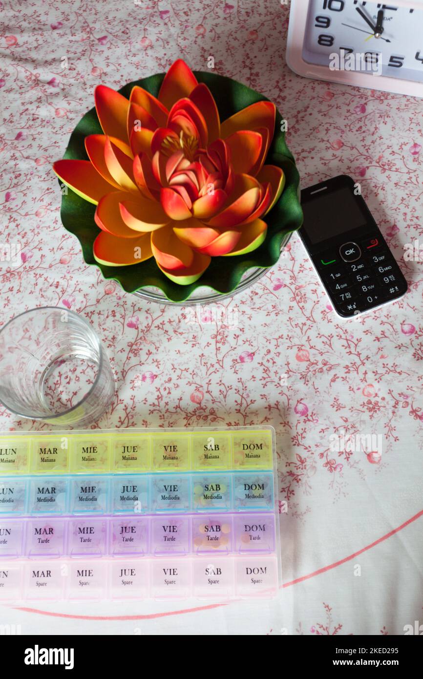 pillbox for the monthly organization of medication on the table next to a glass and mobile phone. Stock Photo