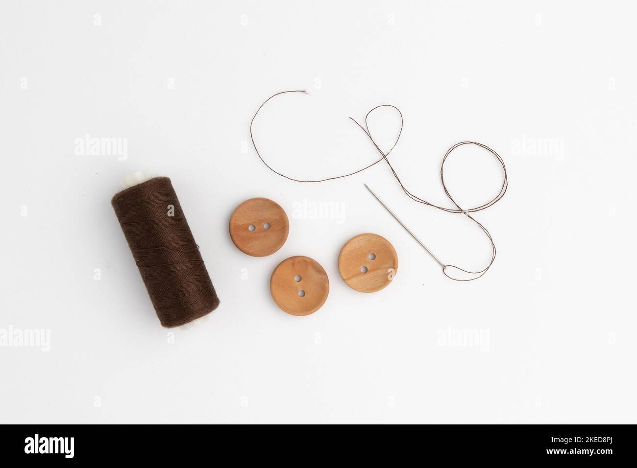 needle with thread and wooden buttons isolated on white background, concept of sewing and repairing clothes Stock Photo