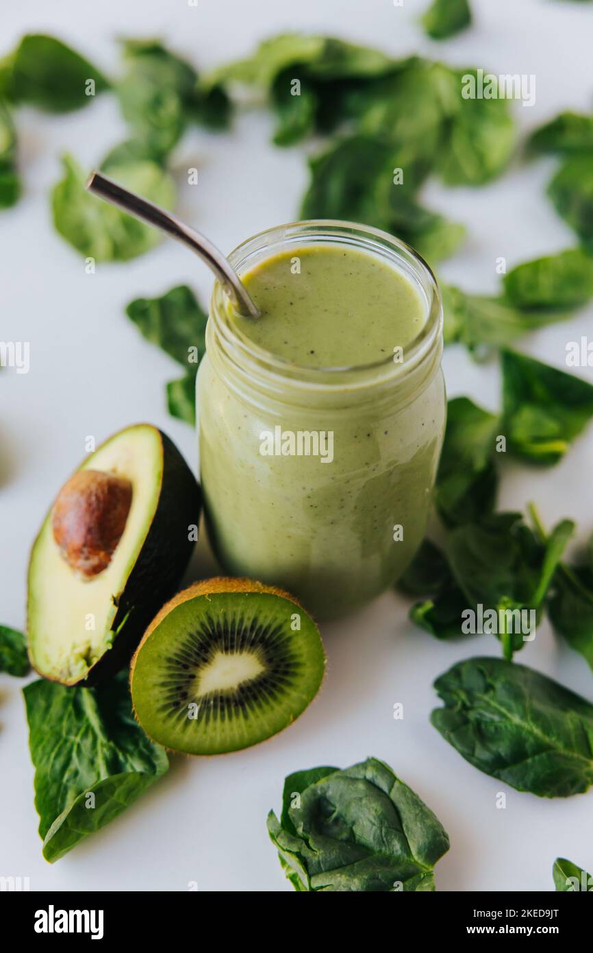 A top view of a jar with a healthy fresh green shake, with a half kiwi