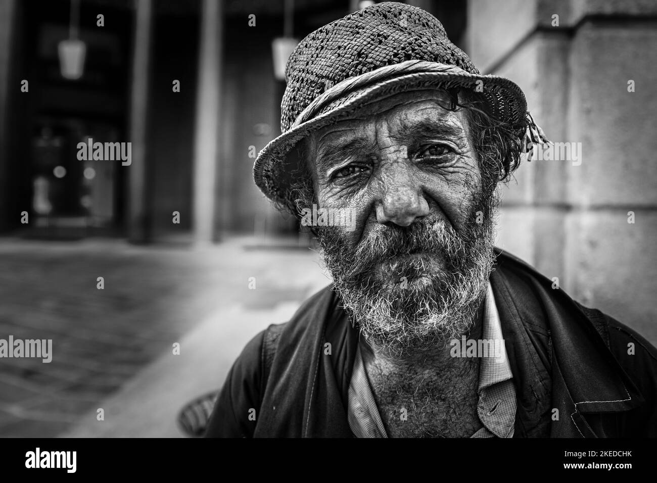 A greyscale portrait of an old male in a street in Milan, Italy Stock Photo