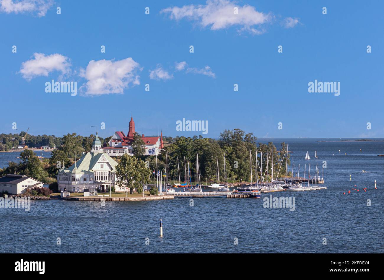Helsinki, Finland - July 19, 2022: Ravintola NLK on its Valkosaari island had green roof. Restaurant Saaristo onn its island has red roof under blue c Stock Photo