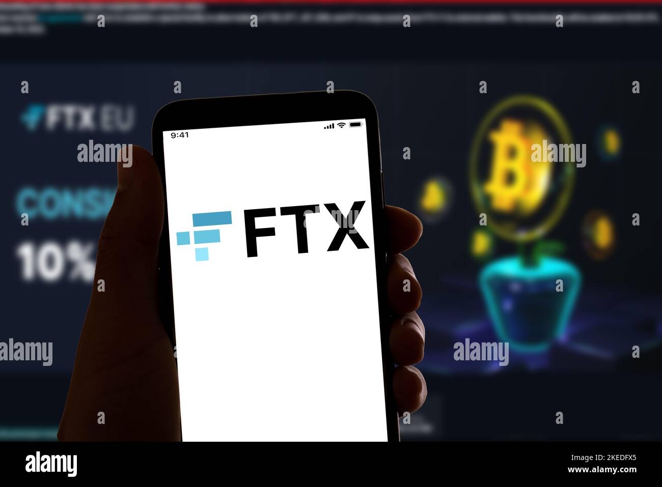 In this photo illustration, the online crypto firm FTX logo is displayed on a smartphone screen with a website homepage in the background. The crypto currency trading platform filed for bankruptcy after a sudden downfall of its stock value. Stock Photo