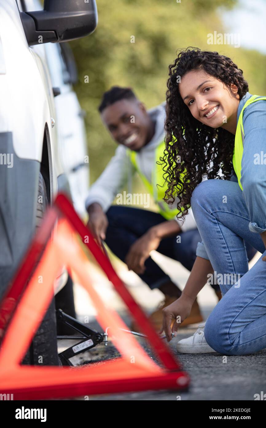 couple after a car breakdown changing wheel Stock Photo