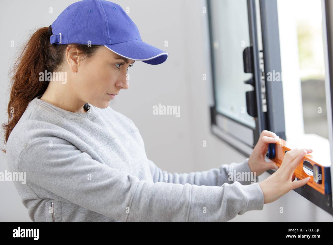 female builder using a spirit level on a window Stock Photo