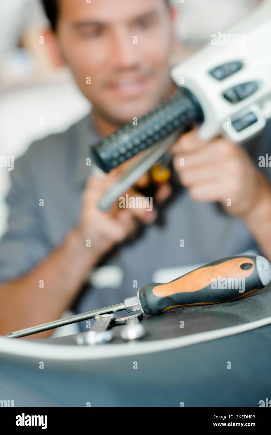 Mechanic working on scooter, blurred background Stock Photo