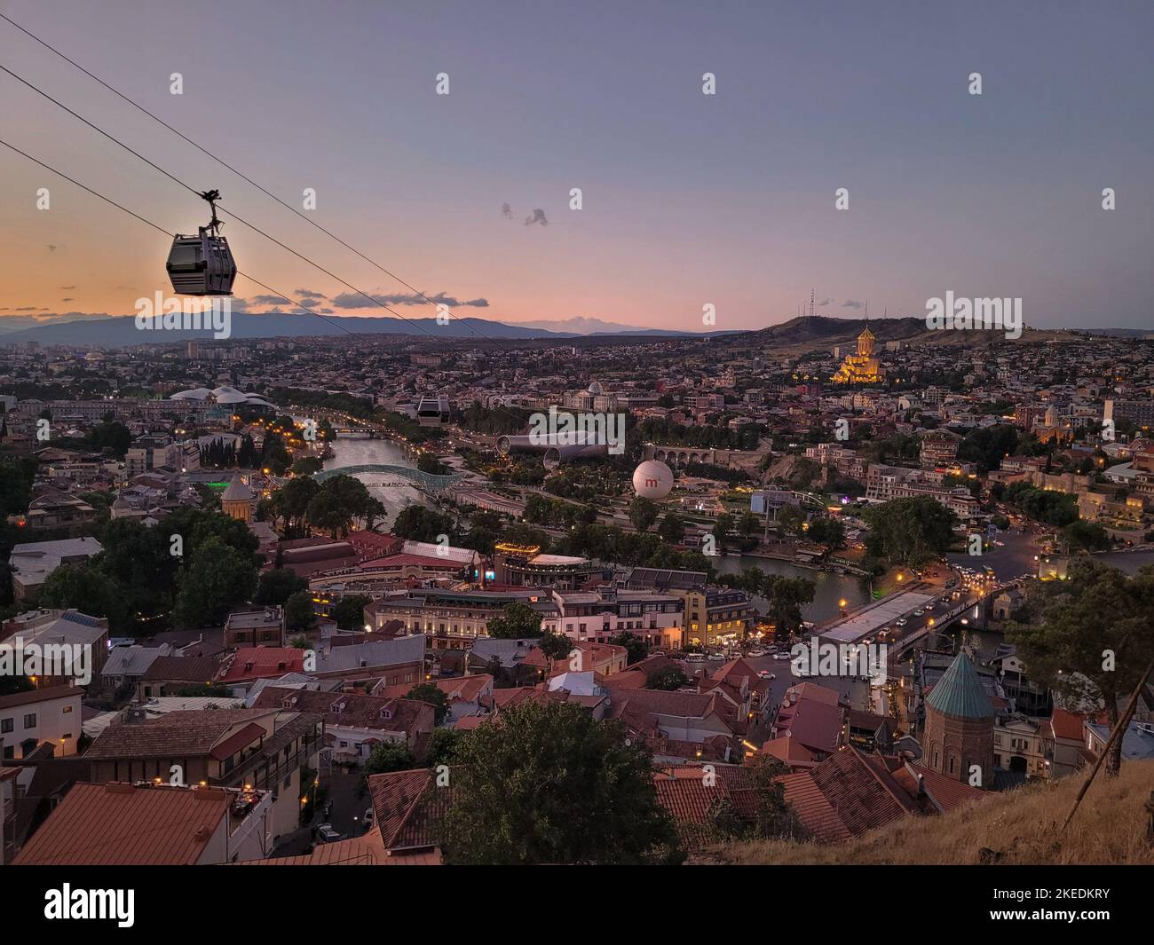 Summer sunset panorama of city of Tbilisi Tiflis, capital of Georgia with Aerial Tramway cable car above streets of Old Tbilisi in foreground, Mtkvari Stock Photo