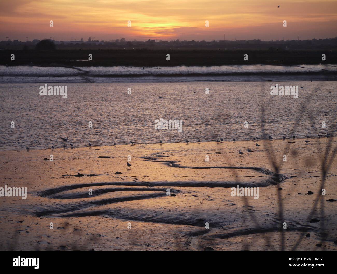 Sunset over the River Adur at low tide with Brighton City Airport runway and Lancing in