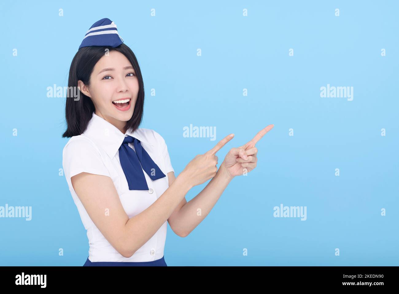Happy Beautiful Airline stewardess showing something on blue background Stock Photo