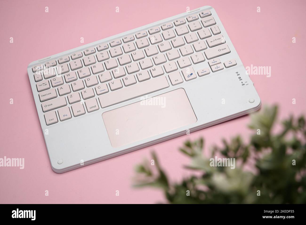 working with wireless external portable keyboard isolated pink background Stock Photo