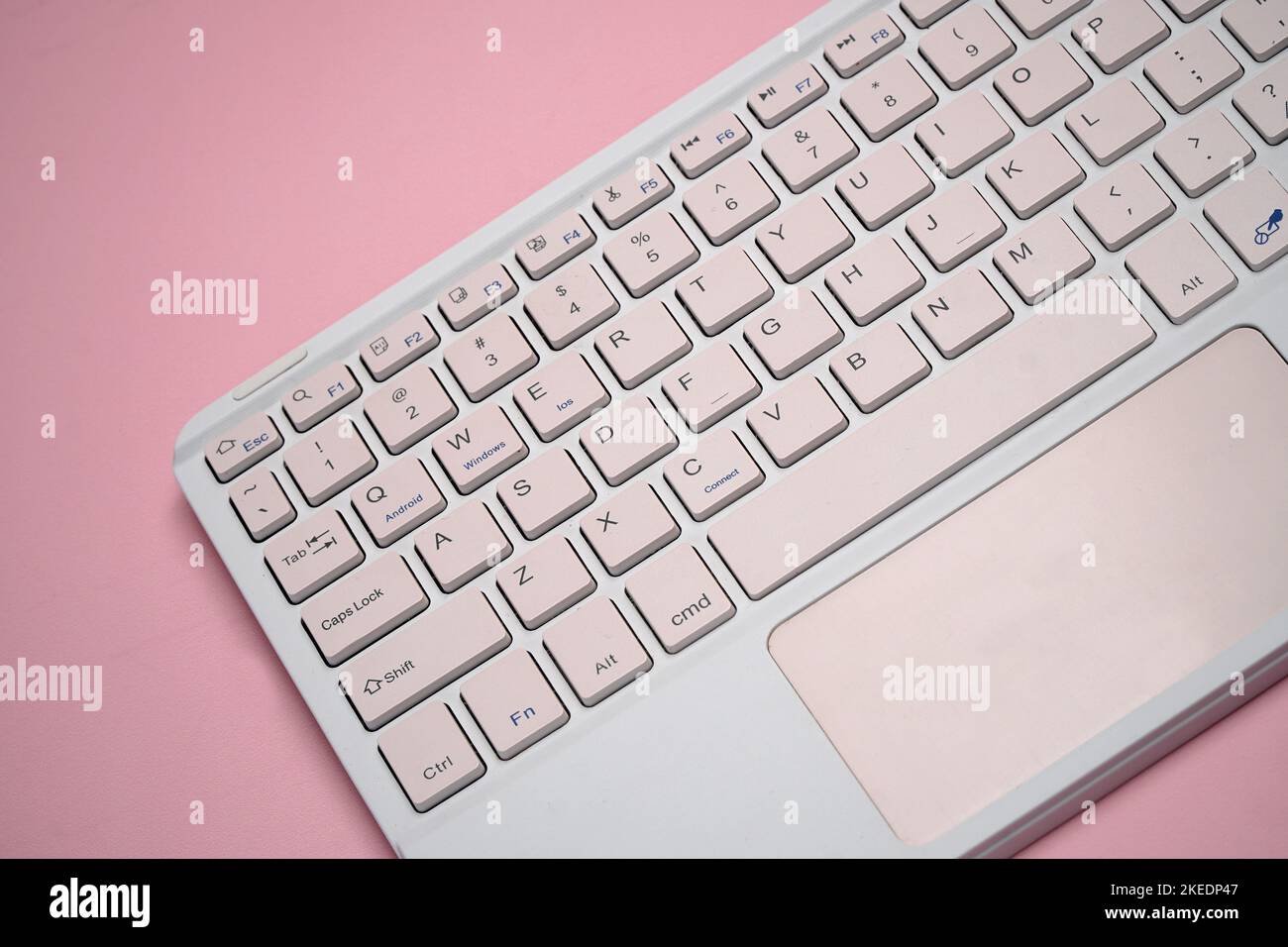 working with wireless external portable keyboard isolated pink background Stock Photo