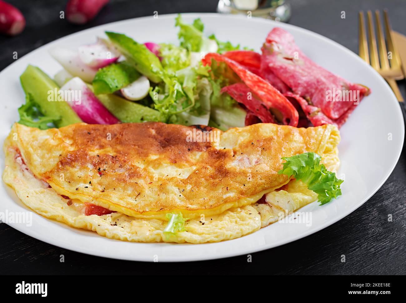 Breakfast. Omelette with cheese and  fresh salad, salami. Frittata - italian omelet. Ketogenic lunch. Stock Photo