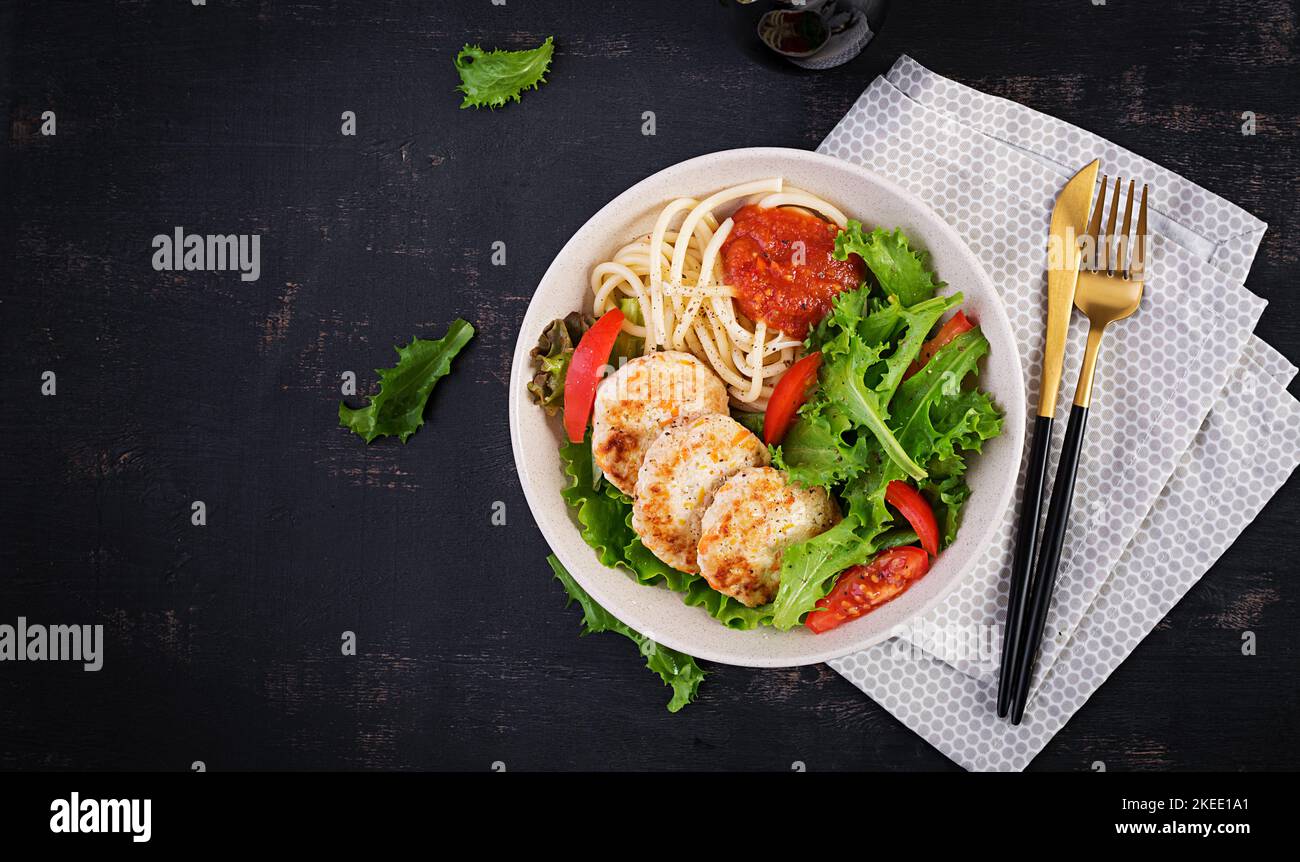 Spaghetti pasta, chicken burgers and salad in bowl. Chicken patties