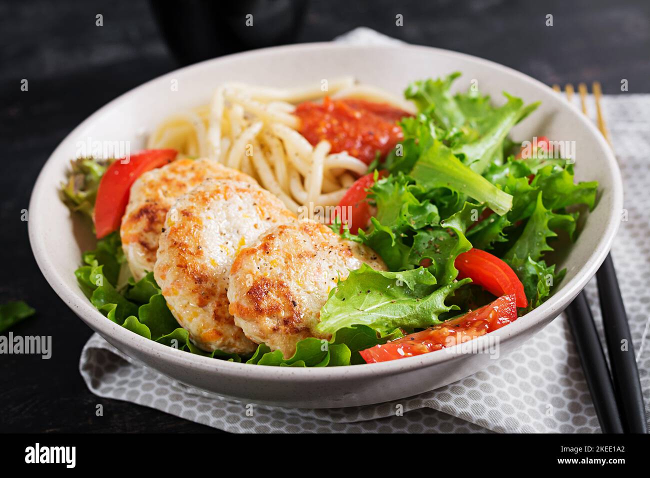 Spaghetti pasta, chicken burgers and salad in bowl. Chicken patties