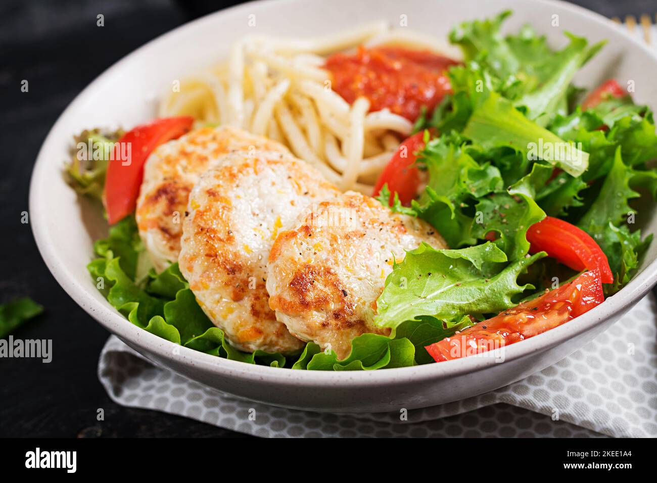 Spaghetti pasta, chicken burgers and salad in bowl. Chicken patties