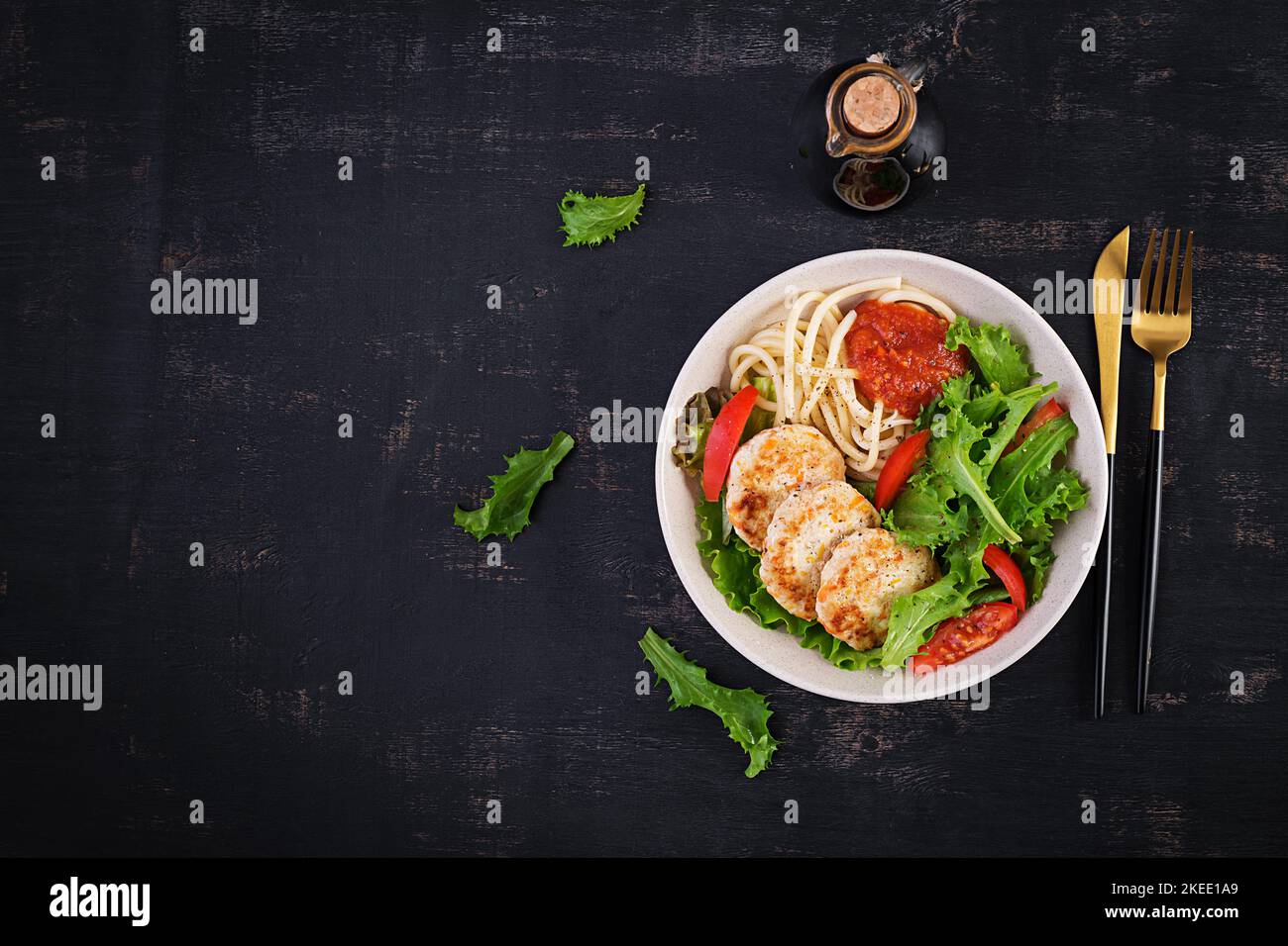 Spaghetti pasta, chicken burgers and salad in bowl. Chicken patties