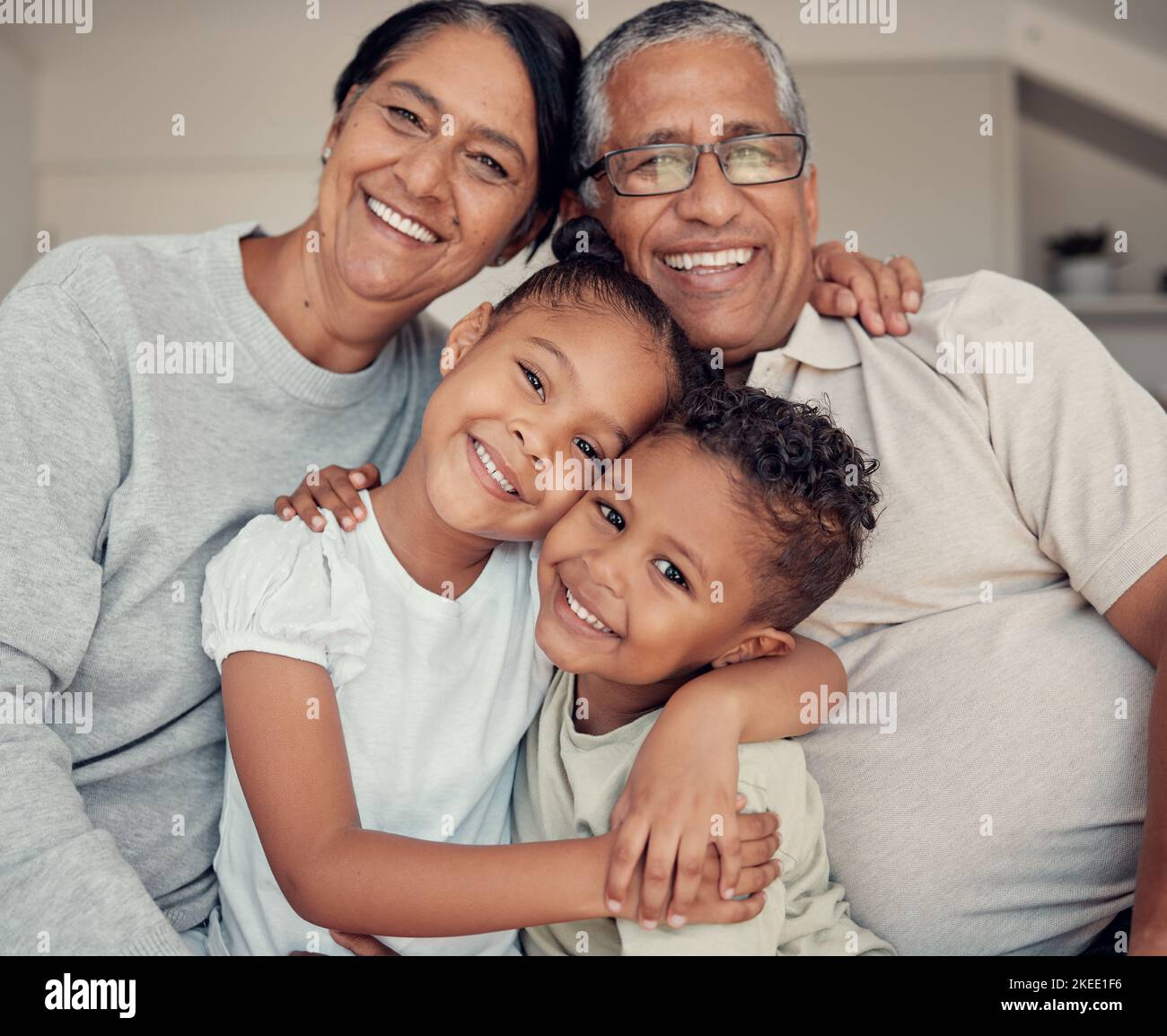 Family portrait, happiness and love of children and grandparents with a smile, hug and support while together on a living room couch at home. Face Stock Photo