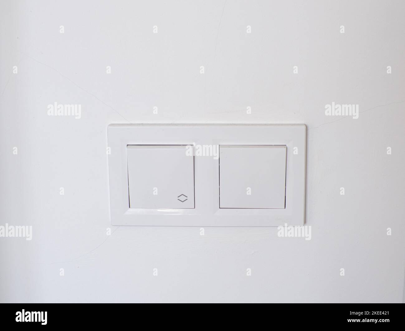 Double white plastic mechanical switches, installed on a white wall