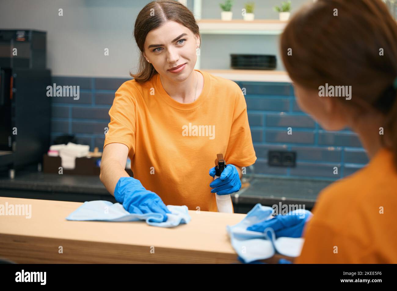 Two female cleaners communicate and clean surfaces in the kitchen area