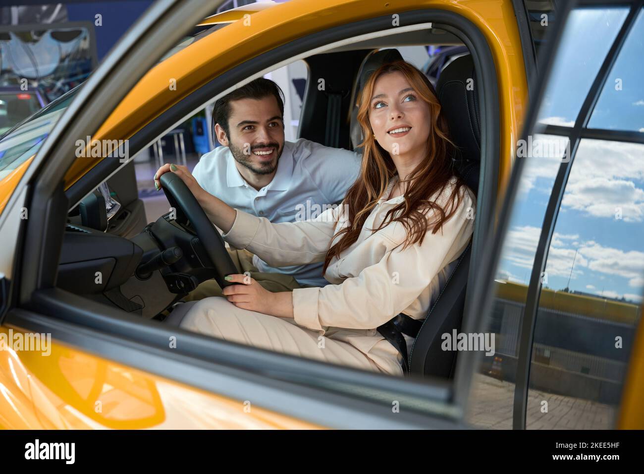 Happy couple of buyers sitting in new car in showroom Stock Photo