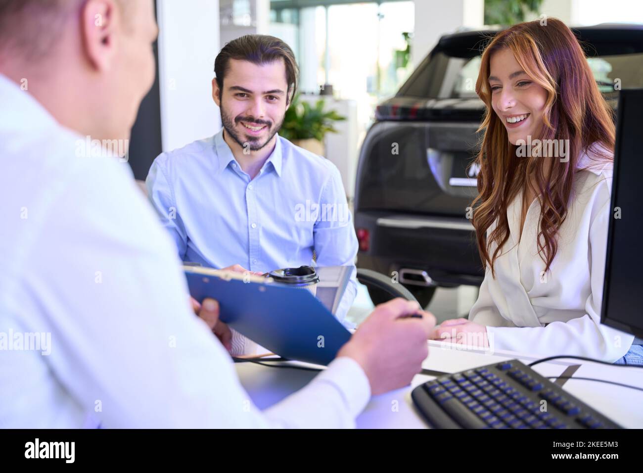 Automotive dealership salesperson demonstrating contract to car buyers