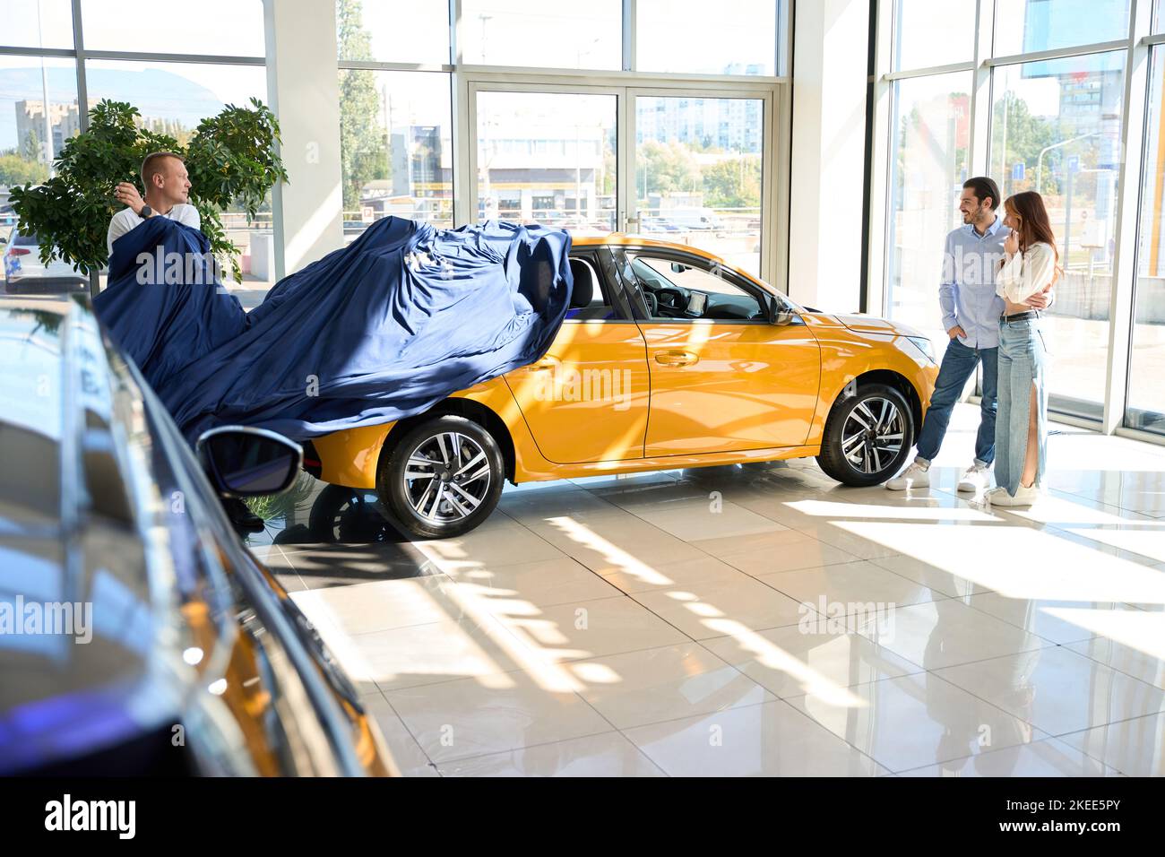 Salesman showing new motorcar to happy buyers Stock Photo