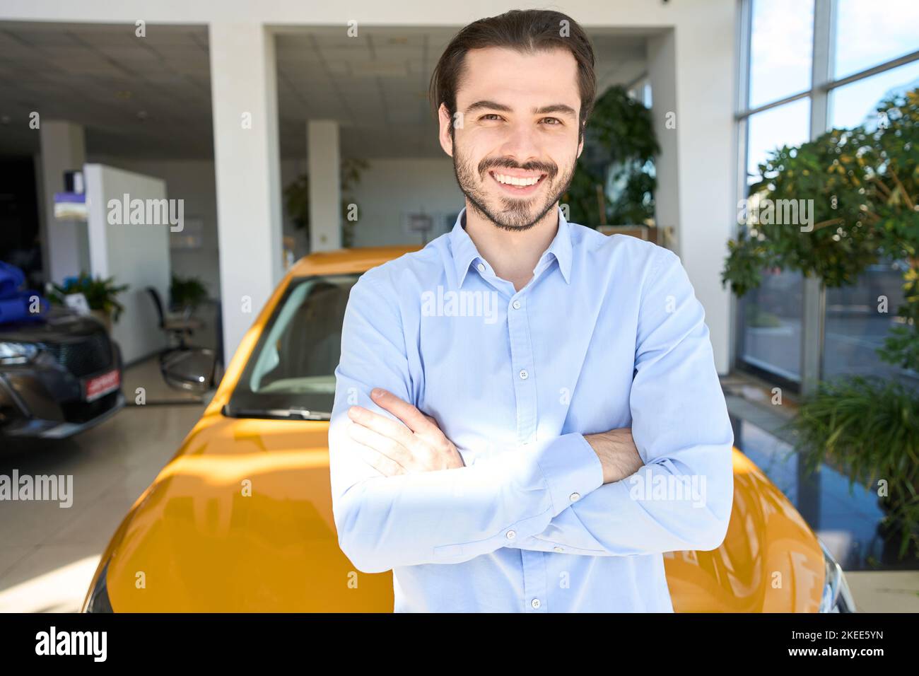 Happy new vehicle owner is posing for camera in showroom Stock Photo
