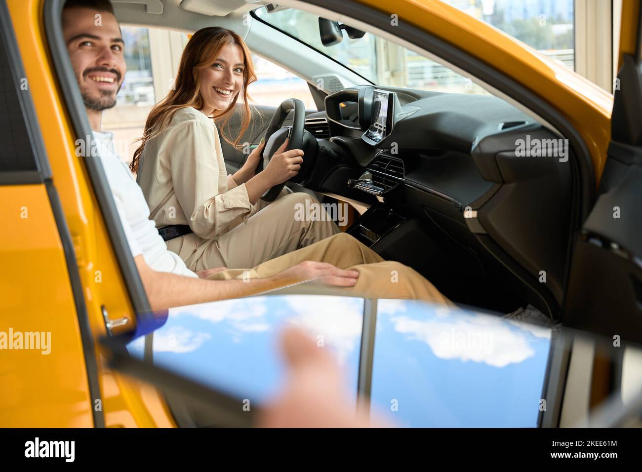 Happy couple sitting in new car in showroom Stock Photo