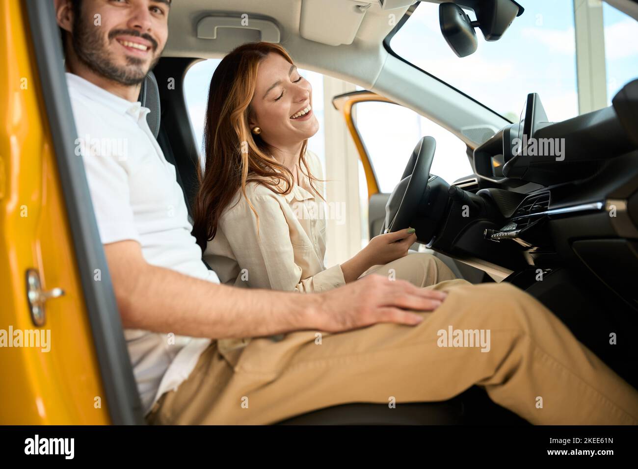 Happy couple seated in new car at dealership Stock Photo