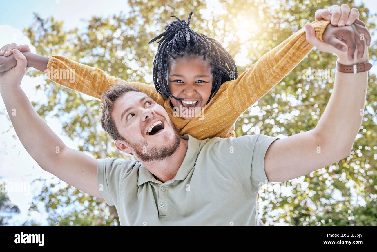 Family, child and adoption piggy back with happy, excited and fun father bonding with daughter in nature. Happiness, care and support of foster dad Stock Photo