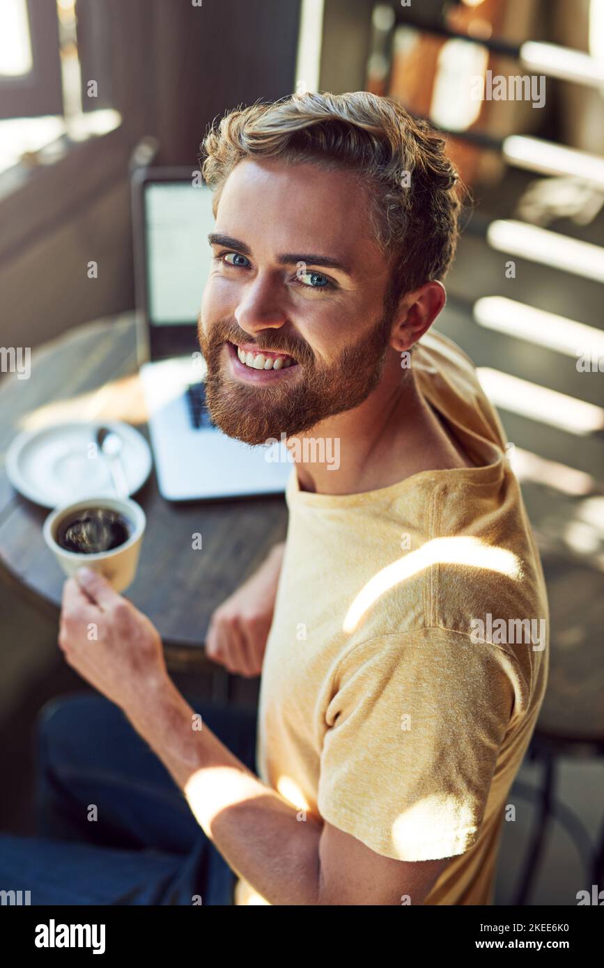 They serve the best coffee here. Portrait of a young using a laptop in a cafe. Stock Photo