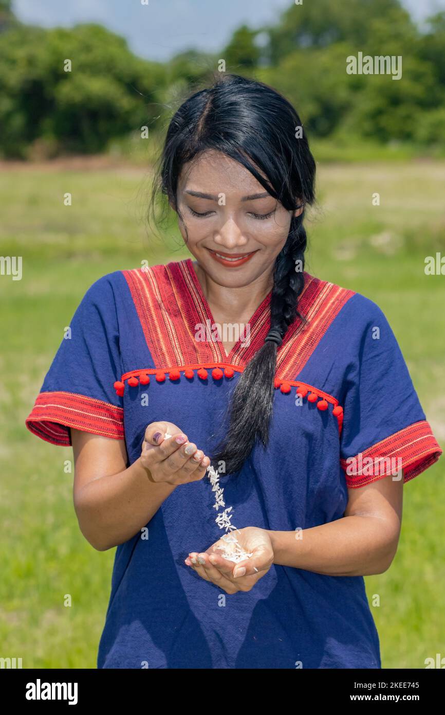 Asian woman in costume pours rice from palm to palm Stock Photo