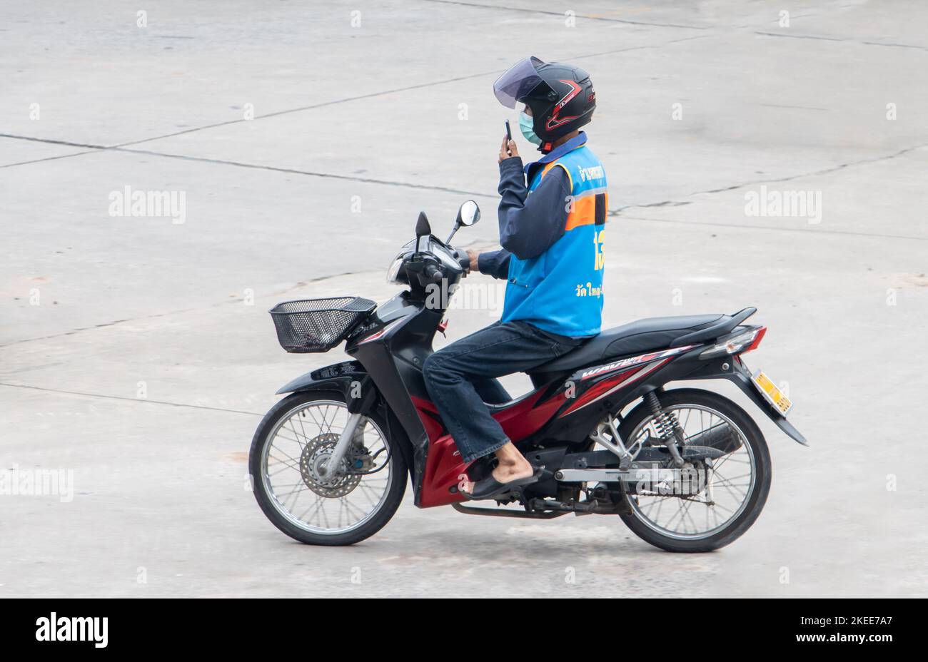 SAMUT PRAKAN, THAILAND, OCT 03 2022, A taxi driver is riding a motorcycle and talking on the phone Stock Photo