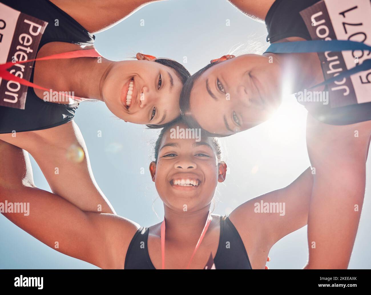 Portrait, women and runners in support huddle after fitness competition from below against blue sky mockup. Sports, friends and trust circle by Stock Photo