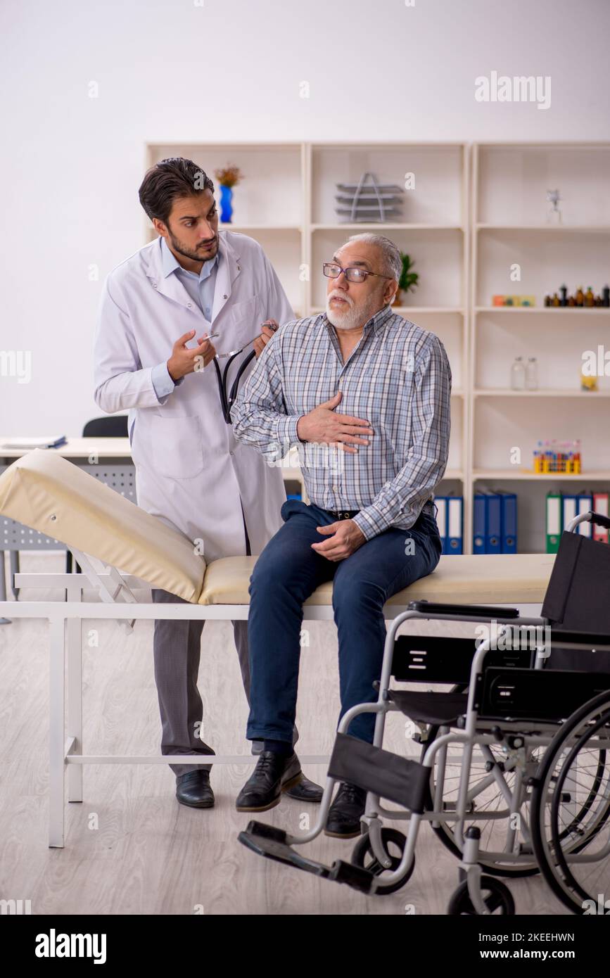 Old male patient in wheelchair visiting young male doctor Stock Photo Alamy