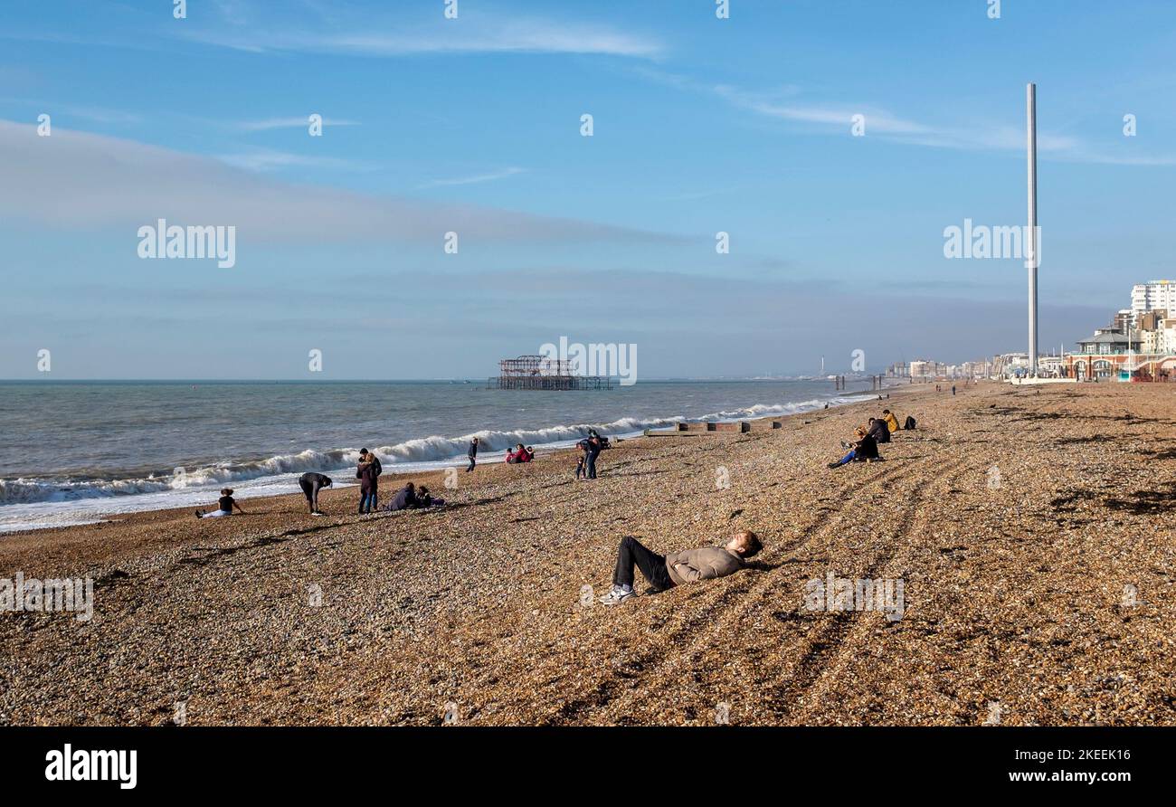 Brighton UK 12th November 2022 - Visitors enjoy a beautiful  sunny morning on Brighton beach and seafront in unusually warm temperatures for the time of year : Credit Simon Dack / Alamy Live News Stock Photo