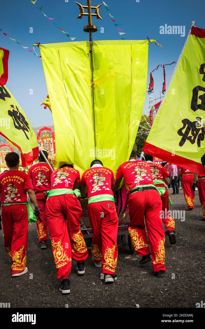 Dragon dance team members push a cart with a ceremonial drum, gong, and pennants at the decennial Da Jiu festival site, Kam Tin, Hong Kong, 2015 Stock Photo