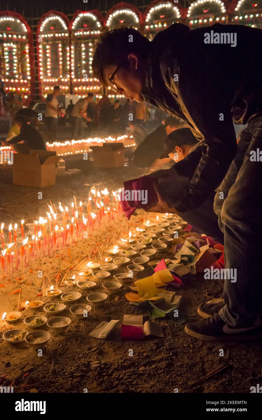 A villager adds joss paper to the other offerings at night at the climactic ceremony of the decennial Da Jiu festival, Kam Tin, Hong Kong, 2015 Stock Photo