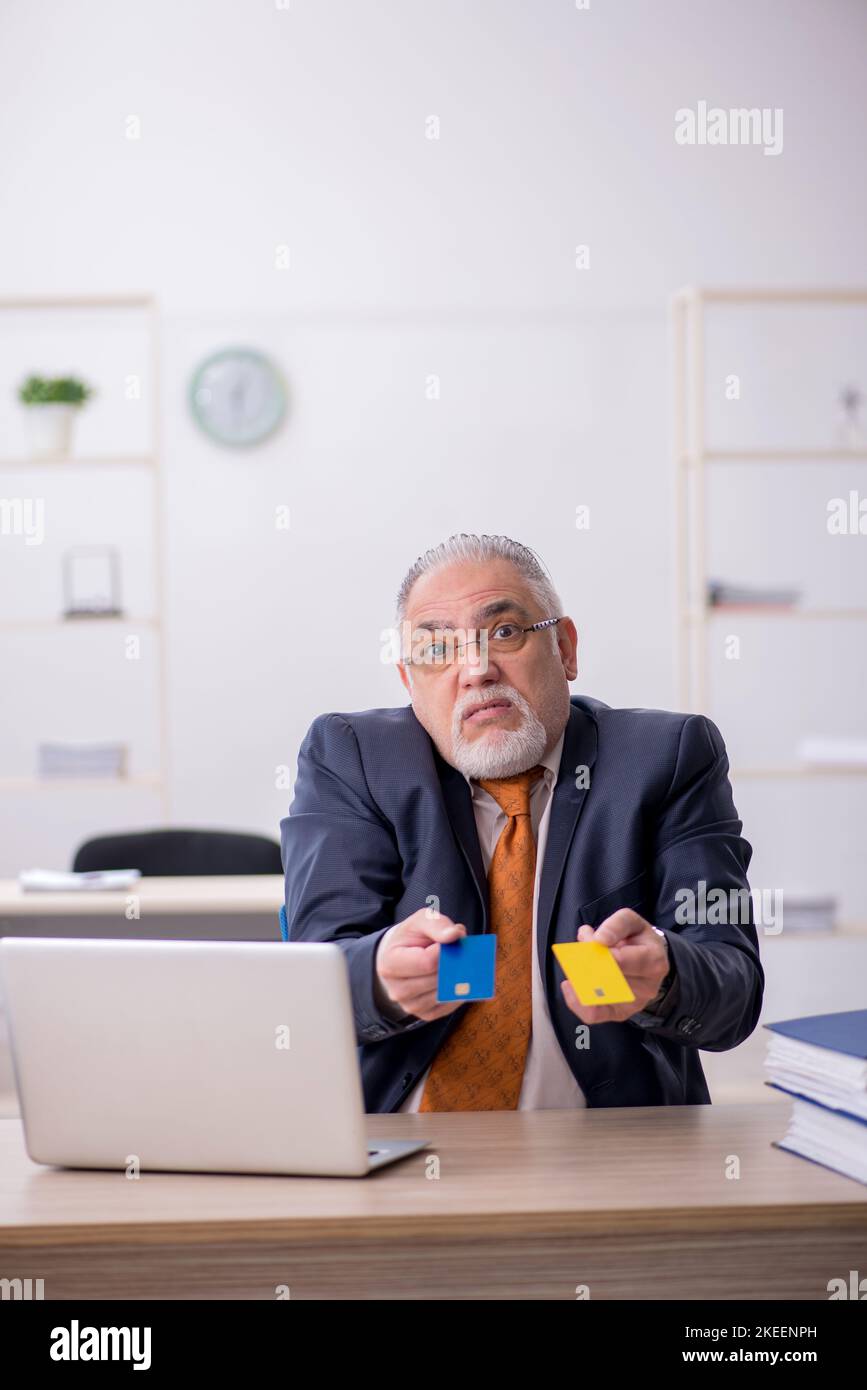 Old businessman employee holding credit card in the office Stock Photo
