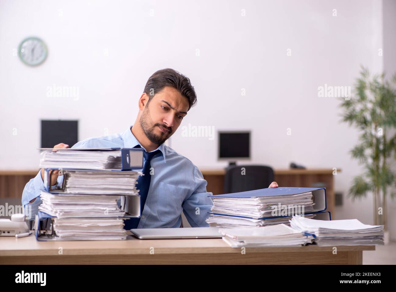 Young businessman employee and too much work at workplace Stock Photo ...
